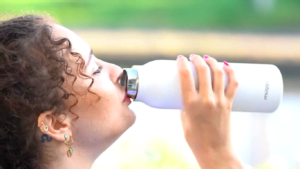 woman drinking from reusable water bottle